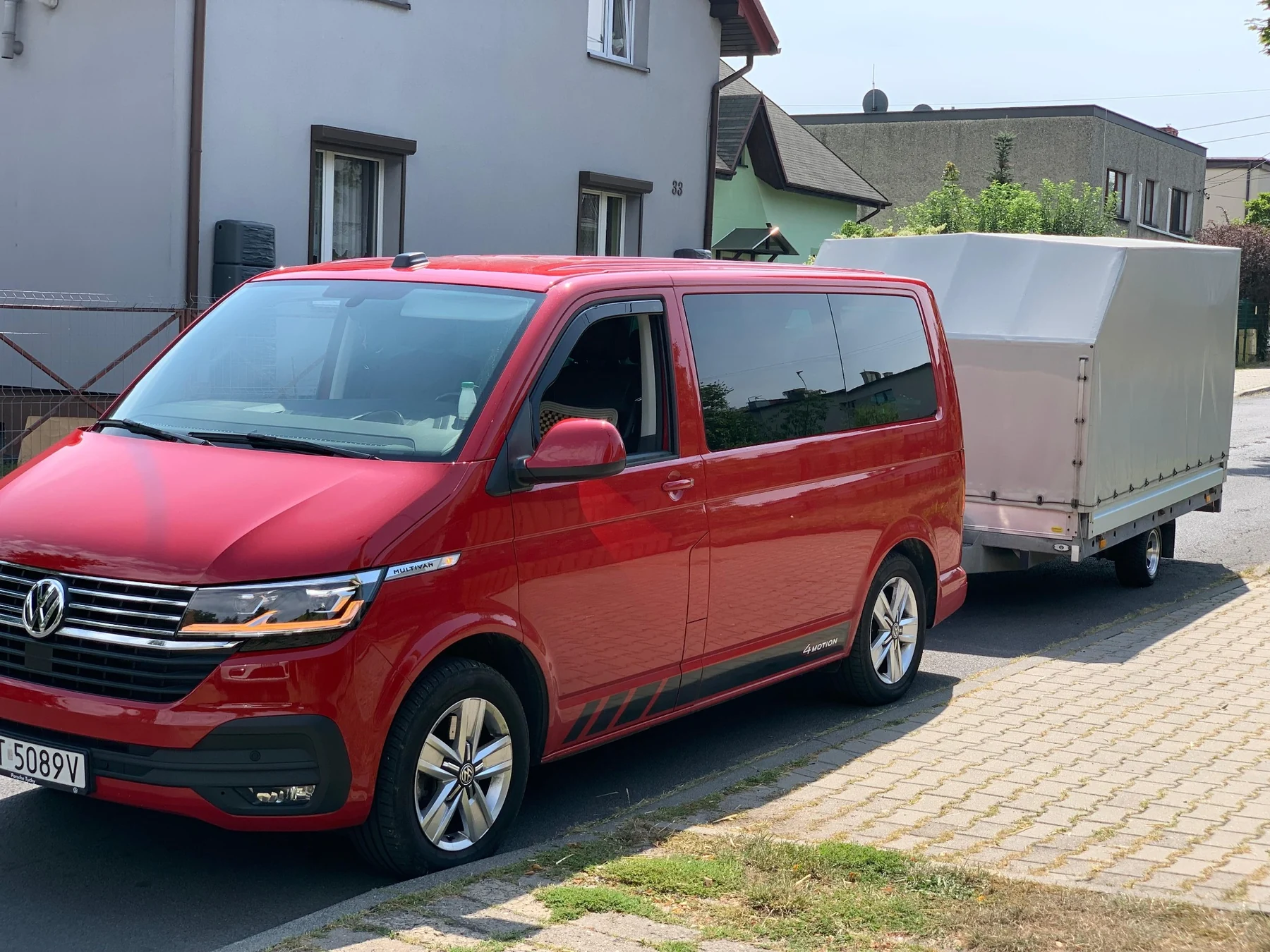 Czerwony Volkswagen Multivan 4Motion z przyczepą