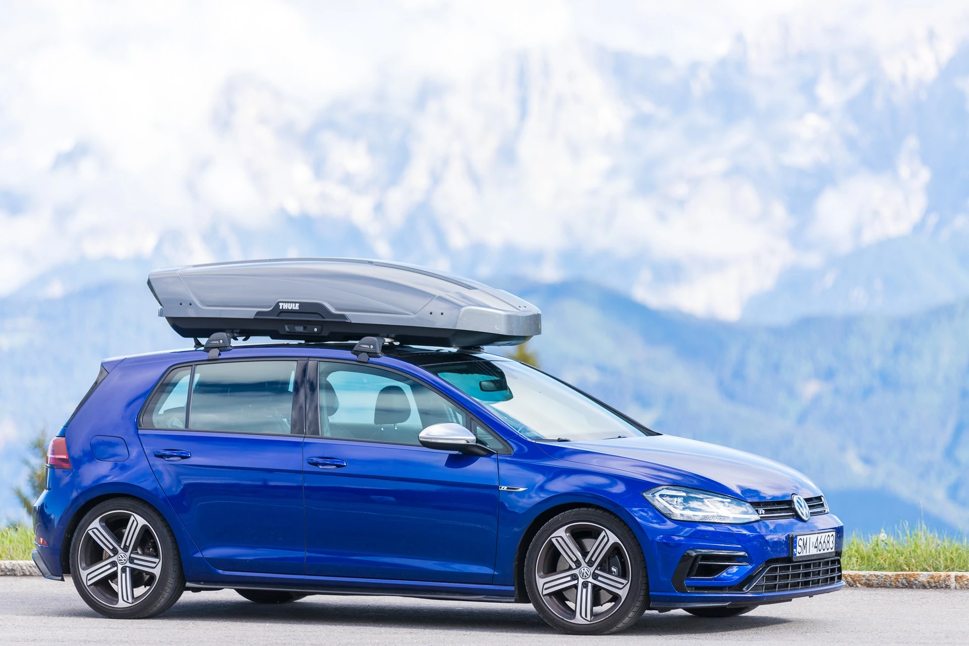 Box dachowy Thule Motion XT XL 500 l w kolorze tytan na niebieskim Volkswagenie Golfie w górach – wynajem Mikołów