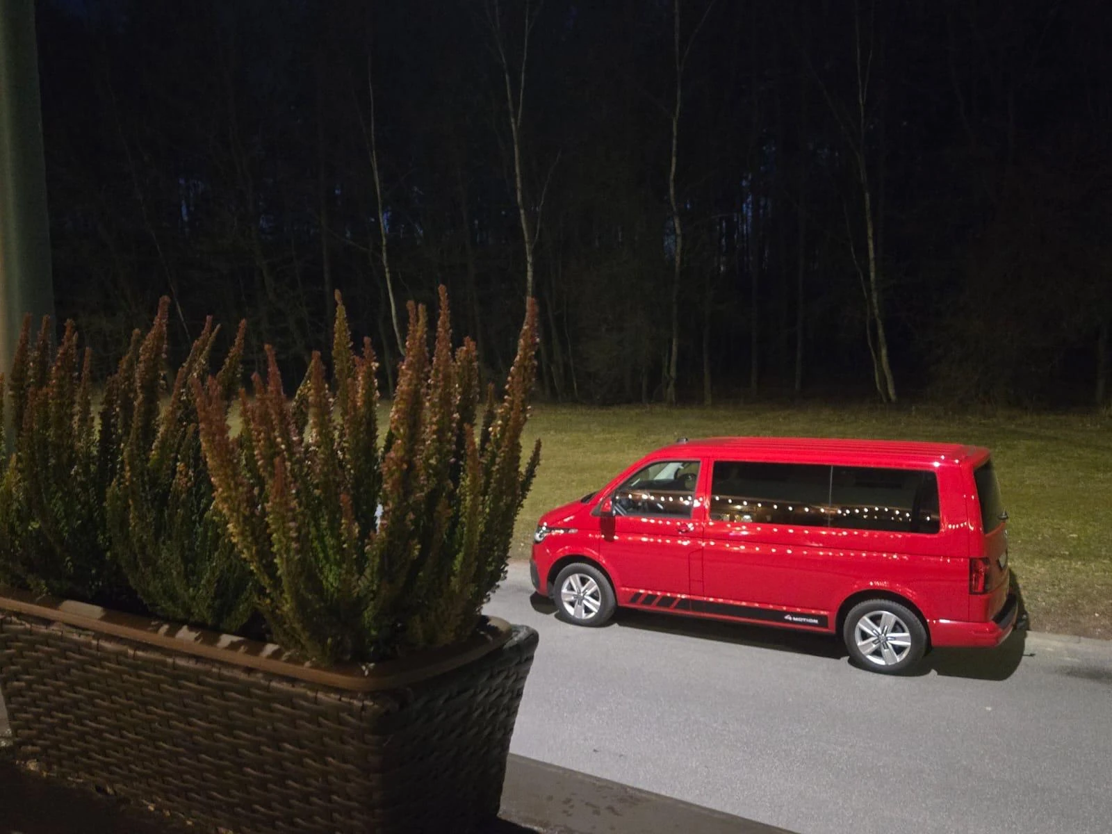 Czerwony Volkswagen Multivan 4Motion podczas nocnego wyjazdu